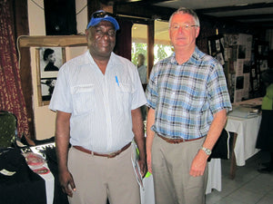 Alastair from Colin Carr Agencies with customer at Trade Show in Honiara, Solomon Islands in front of custom uniform, regalia, ceremonial wear, headwear, footwear
