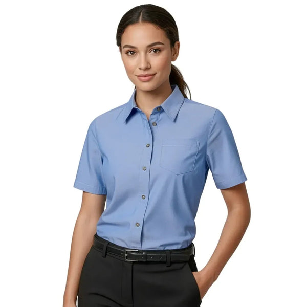 Woman wearing a light blue short-sleeve shirt on a white background. Colin Carr Agencies, professional uniform specialists